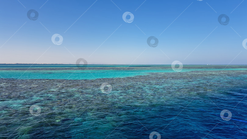 Скачать Бескрайний океанский пейзаж с яркими бирюзовыми водами и коралловыми рифами под ясным голубым небом подчеркивает красоту морских экосистем и спокойствие природы. Красное море. Хургада. Египет фотосток Ozero