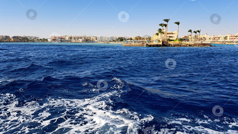 Скачать Яркие голубые океанские волны мягко набегают на далекую береговую линию с пальмами, создавая безмятежную прибрежную атмосферу и приглашая к тропическому отдыху. Красное море. Хургада. Египет фотосток Ozero