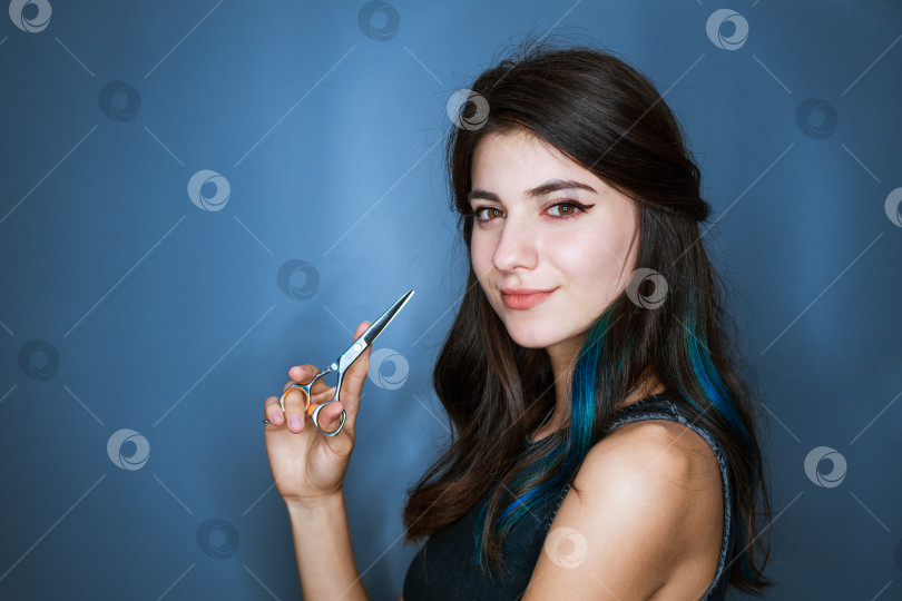 Скачать Симпатичная молодая женщина с брюнеткой с голубыми прядями волос держит ножницы рядом фотосток Ozero
