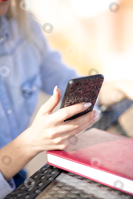 Скачать мобильный телефон в руках женщины. женщина разговаривает по телефону. на заднем плане - стол и дневник фотосток Ozero