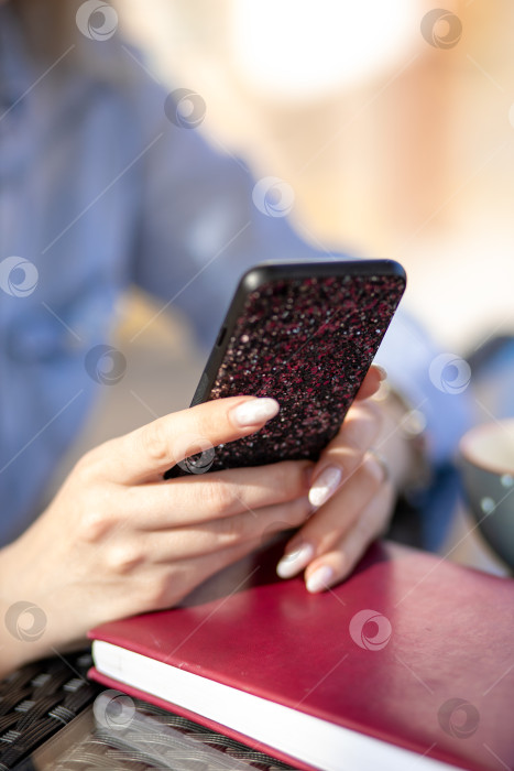 Скачать мобильный телефон в руках женщины. женщина разговаривает по телефону. на заднем плане - стол и дневник фотосток Ozero
