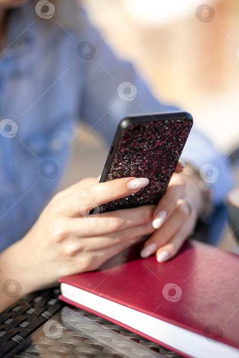 Скачать мобильный телефон в руках женщины. женщина разговаривает по телефону. на заднем плане - стол и дневник фотосток Ozero