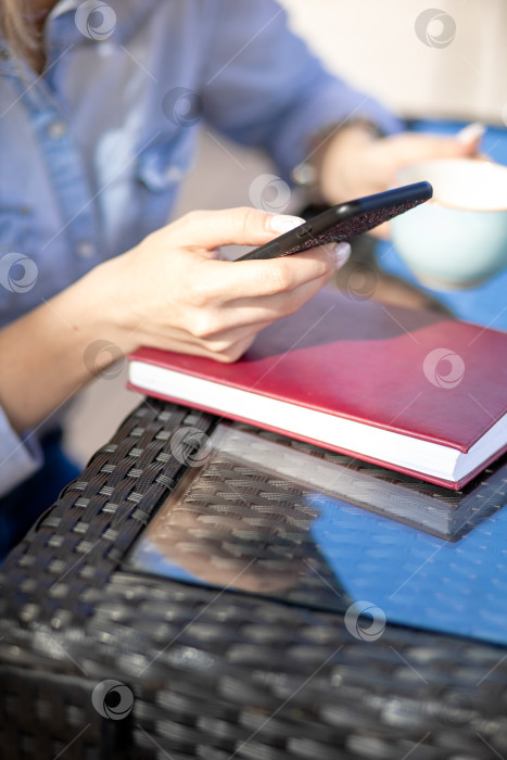 Скачать мобильный телефон в руках женщины. женщина разговаривает по телефону. на заднем плане - стол и дневник фотосток Ozero