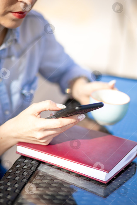 Скачать мобильный телефон в руках женщины. женщина разговаривает по телефону. на заднем плане - стол и дневник фотосток Ozero