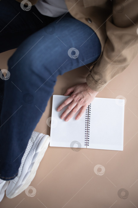 Скачать Вид сверху: Молодая женщина-фрилансер сидит на полу, рядом с открытым блокнотом. Концепция комфортной работы на дому. фотосток Ozero