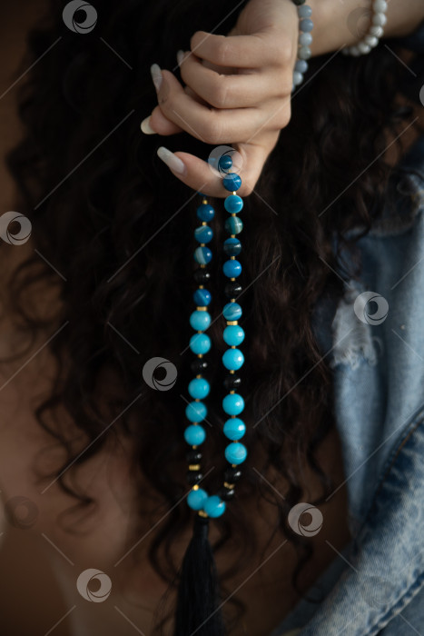 Скачать бусы из натурального камня в женских руках на фоне черных волос фотосток Ozero