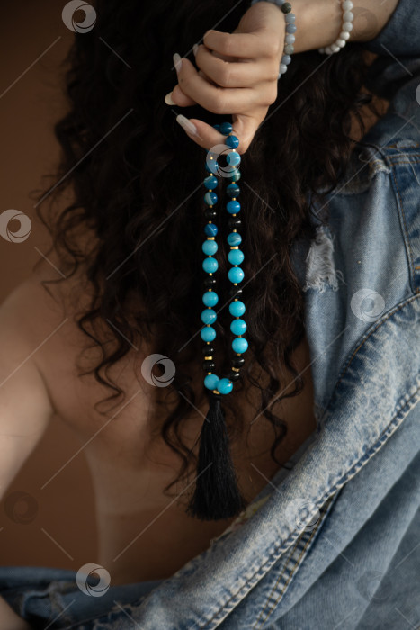 Скачать бусы из натурального камня в женских руках на фоне черных волос фотосток Ozero