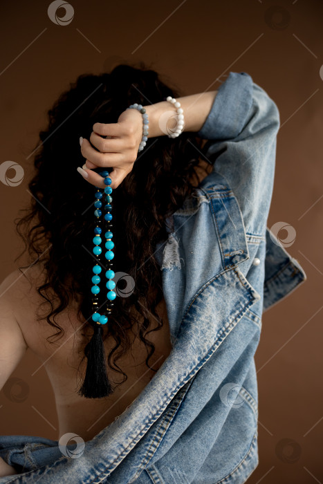 Скачать бусы из натурального камня в женских руках на фоне черных волос фотосток Ozero