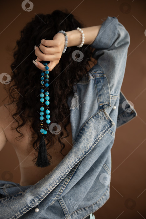 Скачать бусы из натурального камня в женских руках на фоне черных волос фотосток Ozero