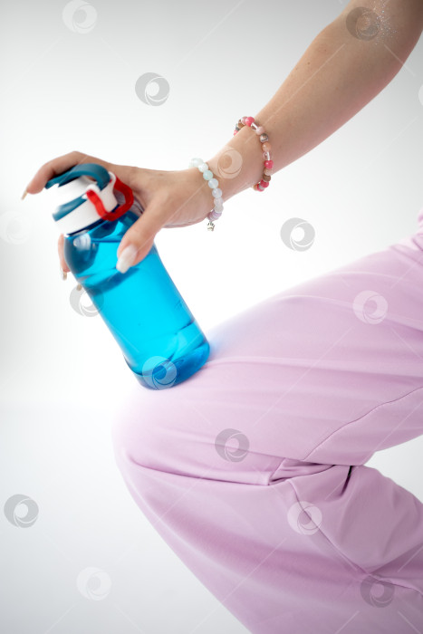 Скачать Синяя бутылка воды в руках женщины, стоящей на коленях фотосток Ozero