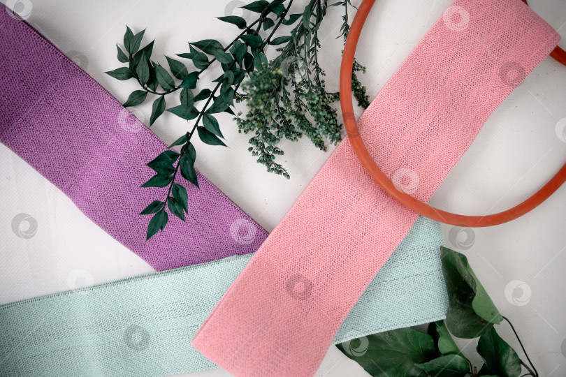 Скачать Крупный план разноцветных галстуков на белом фоне. Розовые фитнес-резинки для спортивного макета фотосток Ozero