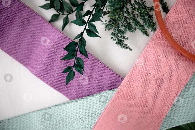 Скачать Крупный план разноцветных галстуков на белом фоне. Розовые фитнес-резинки для спортивного макета фотосток Ozero