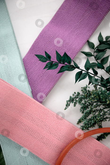 Скачать Крупный план разноцветных галстуков на белом фоне. Розовые фитнес-резинки для спортивного макета фотосток Ozero