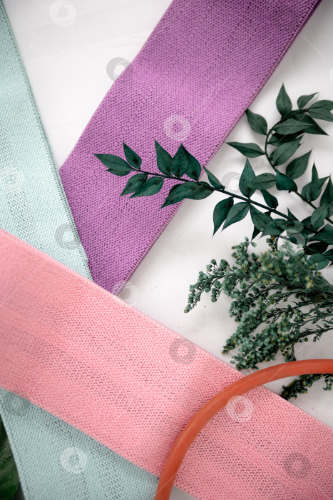 Скачать Крупный план разноцветных галстуков на белом фоне. Розовые фитнес-резинки для спортивного макета фотосток Ozero