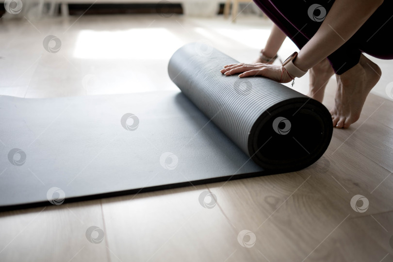 Скачать девушка сворачивает коврик для фитнеса. девушка раскладывает коврик для упражнений в фитнес-студии. Он занимается медитацией и йогой, растягивая свое тело для поддержания здоровья фотосток Ozero