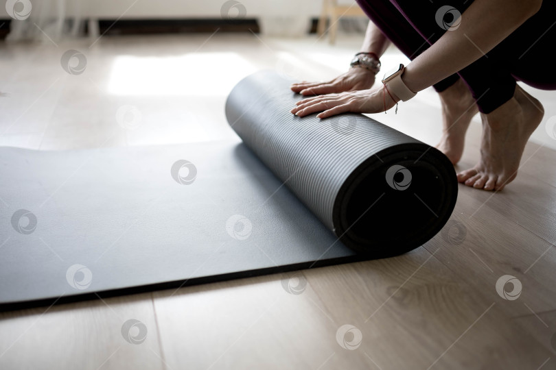 Скачать девушка сворачивает коврик для фитнеса. девушка раскладывает коврик для упражнений в фитнес-студии. Он занимается медитацией и йогой, растягивая свое тело для поддержания здоровья фотосток Ozero