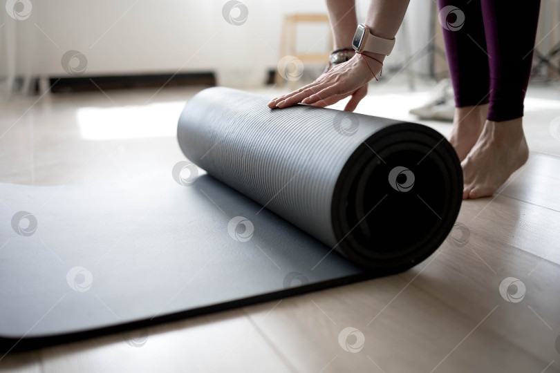 Скачать девушка сворачивает коврик для фитнеса. девушка раскладывает коврик для упражнений в фитнес-студии. Он занимается медитацией и йогой, растягивая свое тело для поддержания здоровья фотосток Ozero
