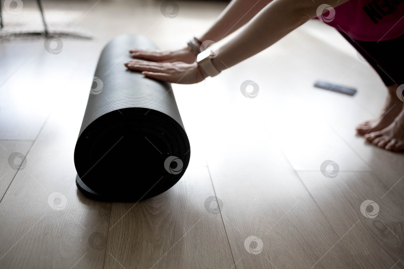 Скачать девушка сворачивает коврик для фитнеса. девушка раскладывает коврик для упражнений в фитнес-студии. Он занимается медитацией и йогой, растягивая свое тело для поддержания здоровья фотосток Ozero