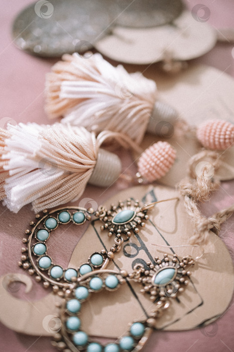 Скачать Набор ручной работы из зеленой, золотистой, бронзовой, слоновой кости и бордовой бижутерии с драгоценными камнями, кисточками, кристаллами и перьями на фоне дерева, фотосток Ozero