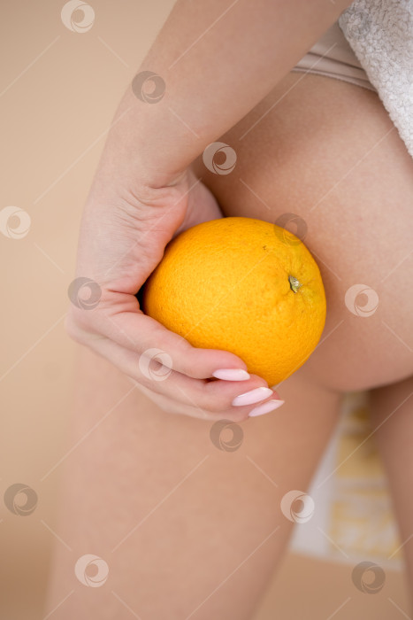 Скачать Женщина в нижнем белье оранжевого цвета на светло-сером фоне, крупным планом. Проблема с целлюлитом фотосток Ozero