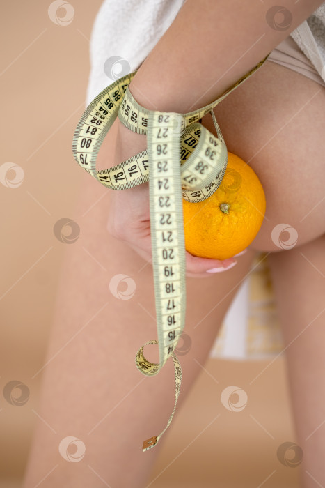 Скачать Женщина в нижнем белье оранжевого цвета на светло-сером фоне, крупным планом. Проблема с целлюлитом фотосток Ozero