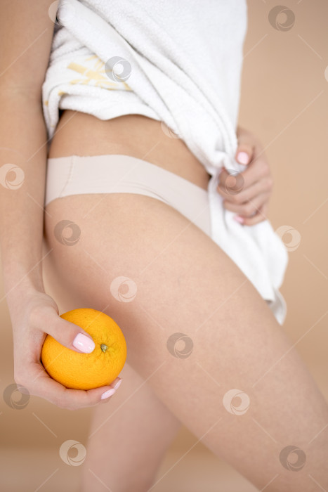 Скачать Женщина в нижнем белье оранжевого цвета на светло-сером фоне, крупным планом. Проблема с целлюлитом фотосток Ozero
