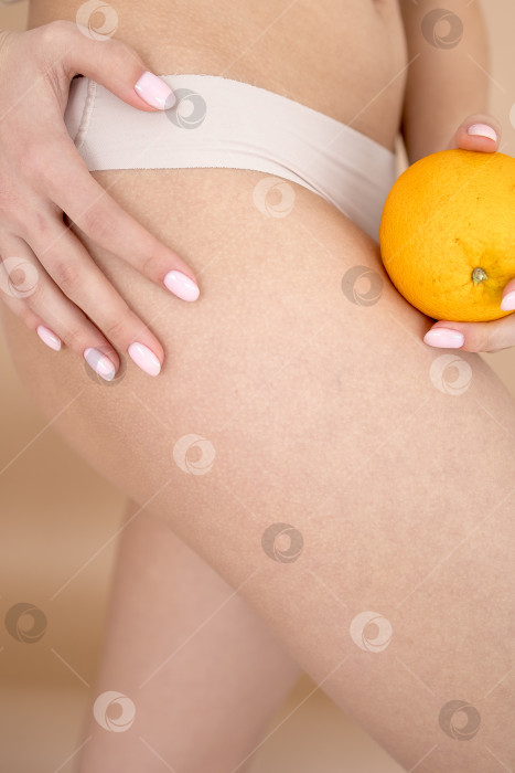 Скачать Женщина в нижнем белье оранжевого цвета на светло-сером фоне, крупным планом. Проблема с целлюлитом фотосток Ozero