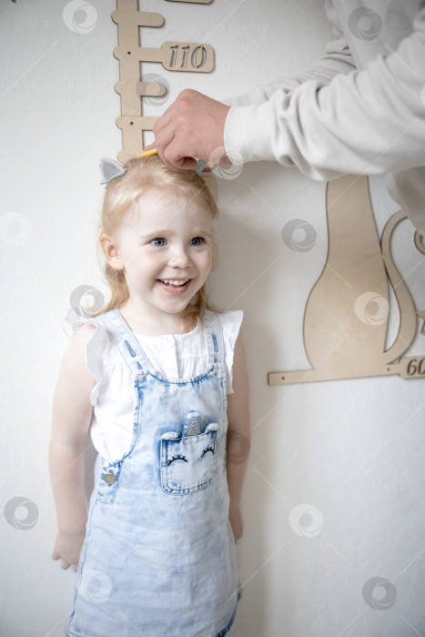 Скачать Маленькая девочка измеряет рост с помощью ростомера фотосток Ozero