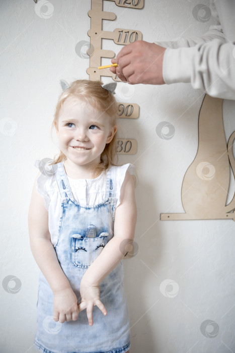 Скачать Маленькая девочка измеряет рост с помощью ростомера фотосток Ozero