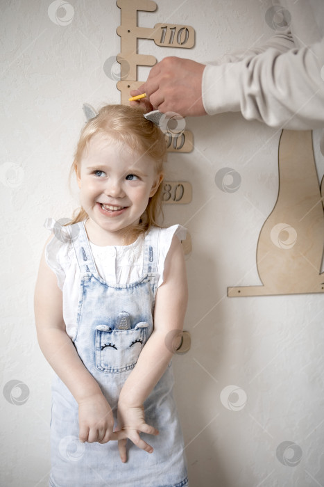 Скачать Маленькая девочка измеряет рост с помощью ростомера фотосток Ozero