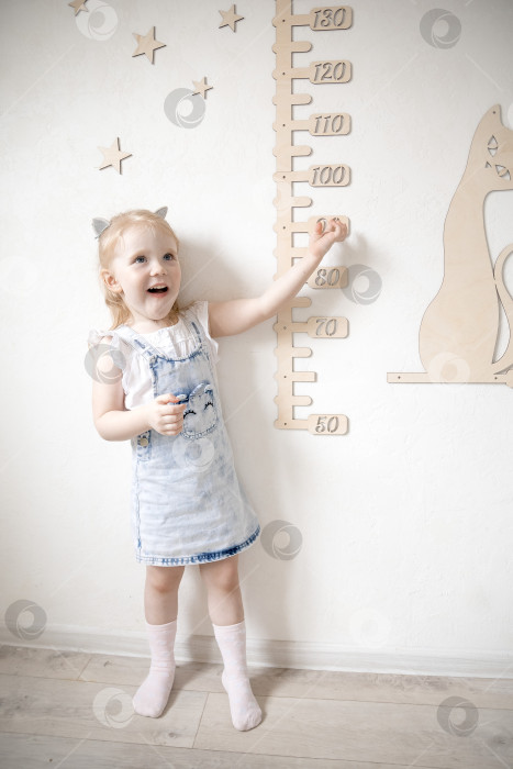 Скачать Маленькая девочка измеряет рост с помощью ростомера фотосток Ozero