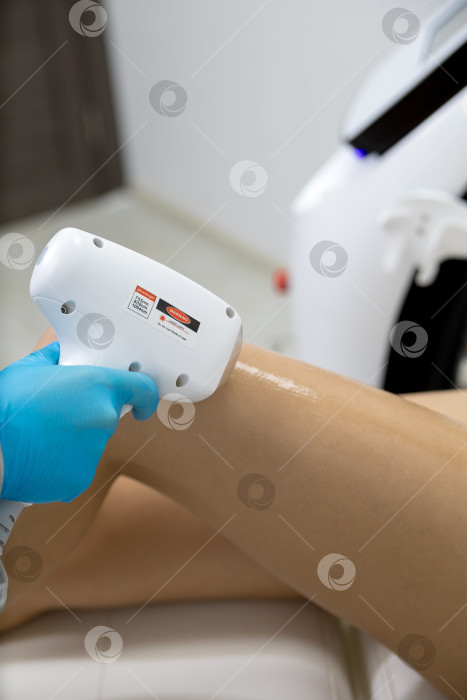 Скачать Процедура удаления волос. На кадре молодая подтянутая клиентка, проходящая процедуру лазерной эпиляции тела в клинике красоты. Концепция женской красоты и косметологии фотосток Ozero