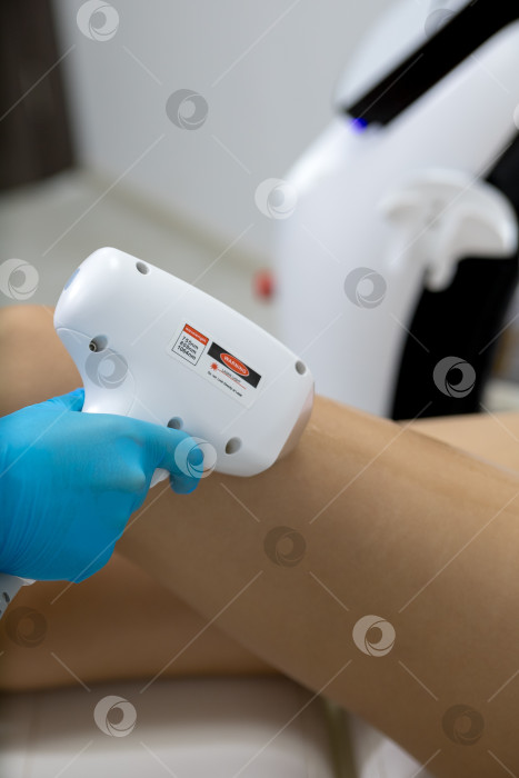 Скачать Процедура удаления волос. На кадре молодая подтянутая клиентка, проходящая процедуру лазерной эпиляции тела в клинике красоты. Концепция женской красоты и косметологии фотосток Ozero