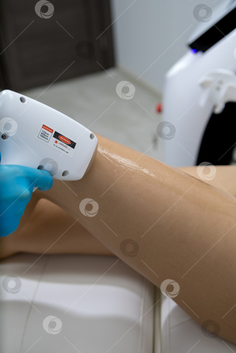 Скачать Процедура удаления волос. На кадре молодая подтянутая клиентка, проходящая процедуру лазерной эпиляции тела в клинике красоты. Концепция женской красоты и косметологии фотосток Ozero