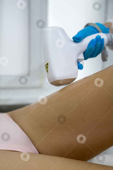 Скачать Процедура удаления волос. На кадре молодая подтянутая клиентка, проходящая процедуру лазерной эпиляции тела в клинике красоты. Концепция женской красоты и косметологии фотосток Ozero