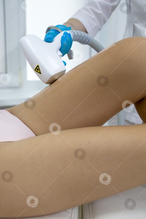 Скачать Процедура удаления волос. На кадре молодая подтянутая клиентка, проходящая процедуру лазерной эпиляции тела в клинике красоты. Концепция женской красоты и косметологии фотосток Ozero