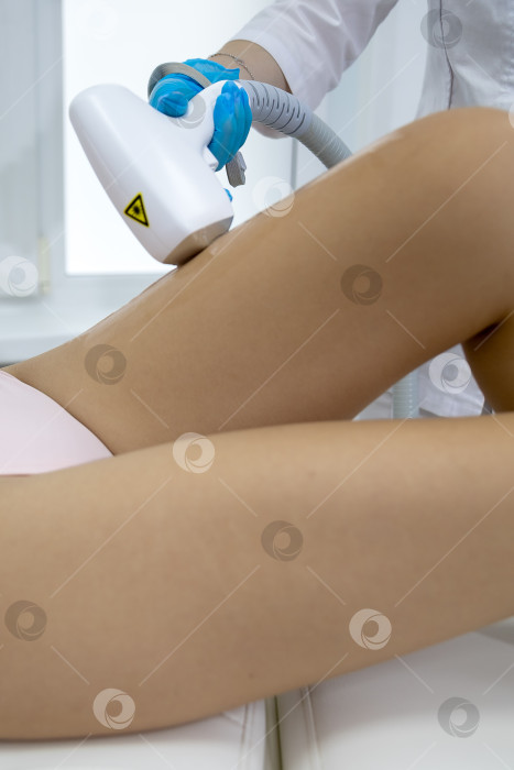 Скачать Процедура удаления волос. На кадре молодая подтянутая клиентка, проходящая процедуру лазерной эпиляции тела в клинике красоты. Концепция женской красоты и косметологии фотосток Ozero