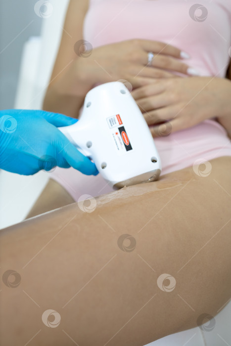 Скачать Процедура удаления волос. На кадре молодая подтянутая клиентка, проходящая процедуру лазерной эпиляции тела в клинике красоты. Концепция женской красоты и косметологии фотосток Ozero