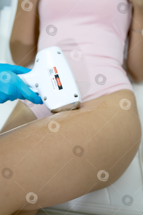 Скачать Процедура удаления волос. На кадре молодая подтянутая клиентка, проходящая процедуру лазерной эпиляции тела в клинике красоты. Концепция женской красоты и косметологии фотосток Ozero