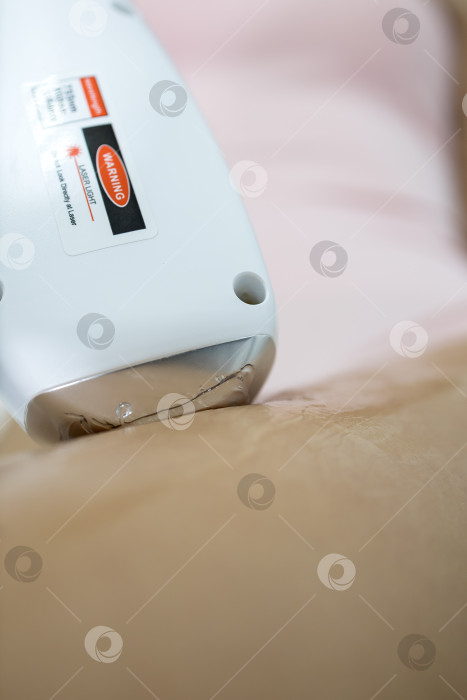 Скачать Процедура удаления волос. На кадре молодая подтянутая клиентка, проходящая процедуру лазерной эпиляции тела в клинике красоты. Концепция женской красоты и косметологии фотосток Ozero