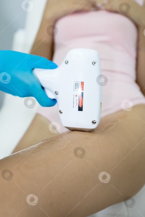 Скачать Процедура удаления волос. На кадре молодая подтянутая клиентка, проходящая процедуру лазерной эпиляции тела в клинике красоты. Концепция женской красоты и косметологии фотосток Ozero