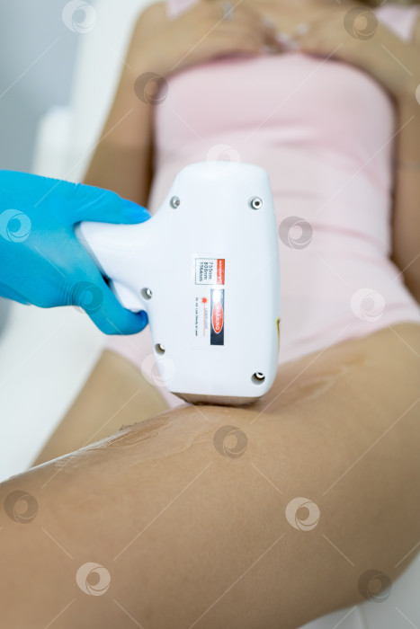 Скачать Процедура удаления волос. На кадре молодая подтянутая клиентка, проходящая процедуру лазерной эпиляции тела в клинике красоты. Концепция женской красоты и косметологии фотосток Ozero