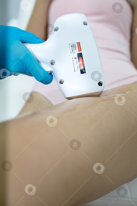 Скачать Процедура удаления волос. На кадре молодая подтянутая клиентка, проходящая процедуру лазерной эпиляции тела в клинике красоты. Концепция женской красоты и косметологии фотосток Ozero