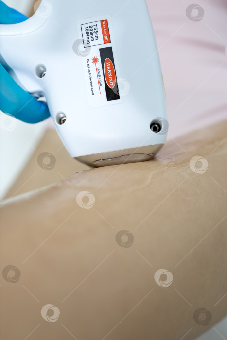 Скачать Процедура удаления волос. На кадре молодая подтянутая клиентка, проходящая процедуру лазерной эпиляции тела в клинике красоты. Концепция женской красоты и косметологии фотосток Ozero