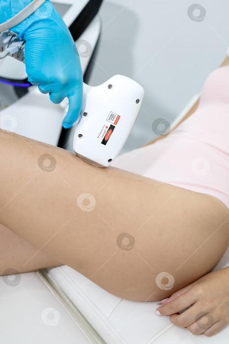 Скачать Процедура удаления волос. На кадре молодая подтянутая клиентка, проходящая процедуру лазерной эпиляции тела в клинике красоты. Концепция женской красоты и косметологии фотосток Ozero