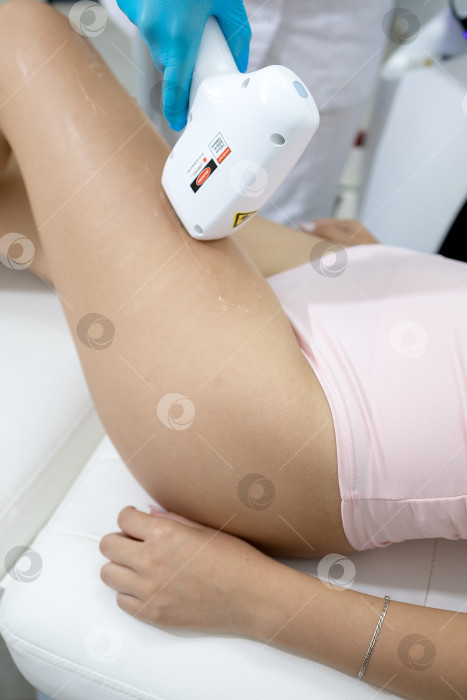 Скачать Процедура удаления волос. На кадре молодая подтянутая клиентка, проходящая процедуру лазерной эпиляции тела в клинике красоты. Концепция женской красоты и косметологии фотосток Ozero