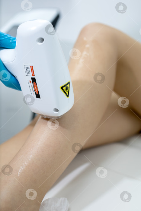 Скачать Процедура удаления волос. На кадре молодая подтянутая клиентка, проходящая процедуру лазерной эпиляции тела в клинике красоты. Концепция женской красоты и косметологии фотосток Ozero