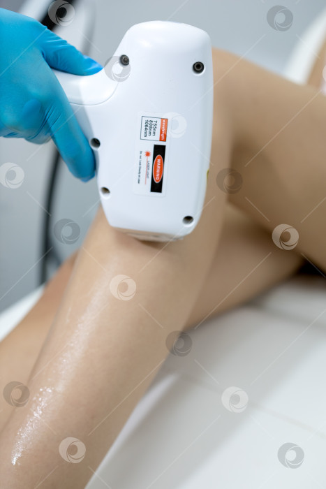 Скачать Процедура удаления волос. На кадре молодая подтянутая клиентка, проходящая процедуру лазерной эпиляции тела в клинике красоты. Концепция женской красоты и косметологии фотосток Ozero