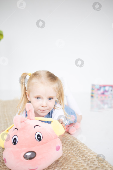 Скачать Счастливая девочка с мягкой игрушкой на белом фоне фотосток Ozero