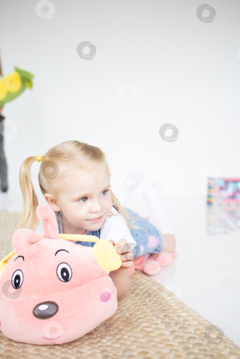 Скачать Счастливая девочка с мягкой игрушкой на белом фоне фотосток Ozero